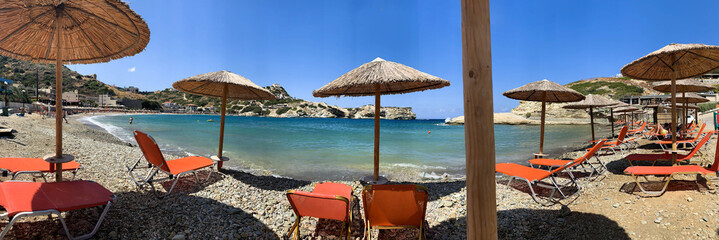 Crete Island, Greece. Summer greek beach panorama with turquoise sea water waves and umbrellas....