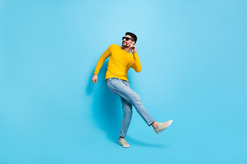 Full length photo of excited cool guy dressed yellow pullover dark eyewear dancing isolated blue color background
