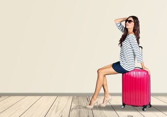 Happy young woman sitting on bright suitcase for travel agency ad. Cheerful female traveler with luggage going on summer vacation