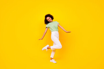 Full length photo of pretty sweet girl dressed green t-shirt dancing walking isolated yellow color background
