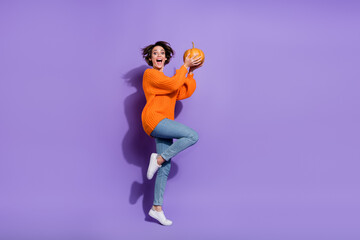 Fototapeta na wymiar Full length body size view of nice childish girl jumping hold pumpkin having fun isolated on bright purple violet color background