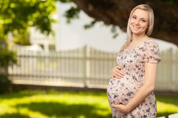 Pregnant woman walking in park during summer. Pregnancy care