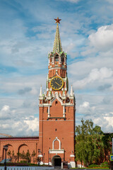 Spasskaya Tower with chimes in the Kremlin against the background of white clouds on a clear sunny day, Moscow. Sights of Russia. Architecture of World Tourism.