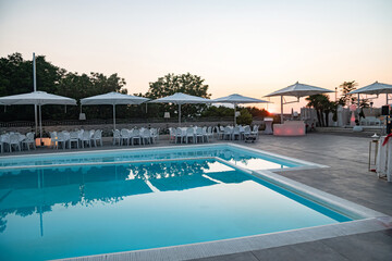 Fototapeta na wymiar Blue swimming pool in a spa hotel in southern Italy at sunset.