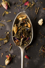 photo of spoon with tea strands and dried flowers on gray background 