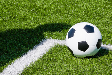 Soccer football sport background. Soccer ball and shadow of player on artificial turf soccer field in sunny day outdoors