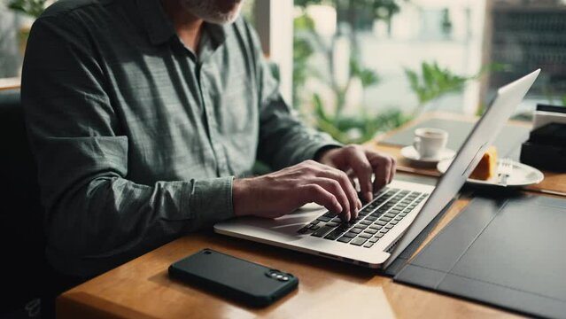 Closeup businessman hands typing on laptop keyboard working remotely at cafe place