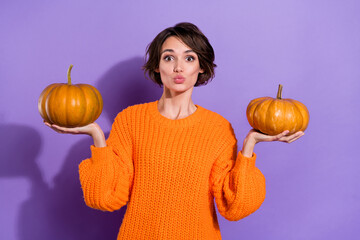 Portrait of attractive funny brown-haired girl holding on palms two pumpkins pout lips isolated on...