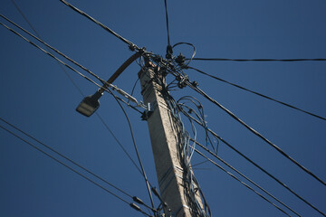 An electric pole with wires and a street lighting lamp