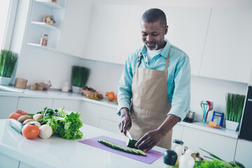 Photo of funny positive age man wear apron preparing supper cutting tasty vegetables indoors room home