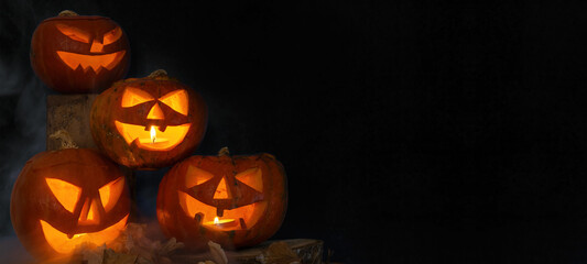 Scary Halloween celebration holiday background banner panorama - Spooky carved pumpkins and dust in the dark black night