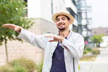 young man with summer hat dancing in a green city