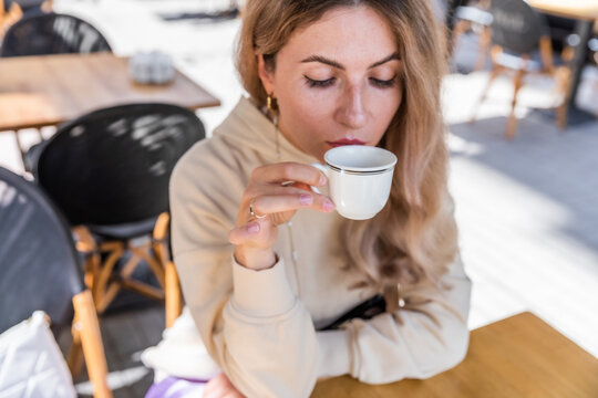 The girl is looking at a white mug of coffee