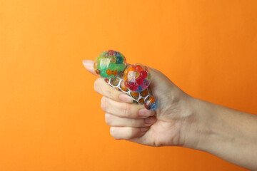 Woman squeezing colorful slime on orange background, closeup. Antistress toy