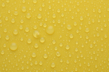 Water drops on yellow background, top view