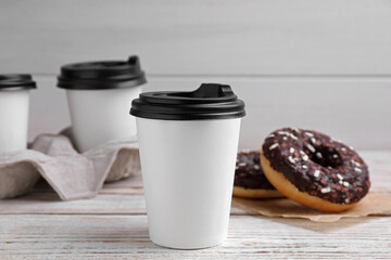 Cups of hot drinks and tasty donuts on white wooden table
