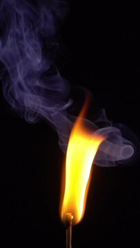 a lit match burns on a black background vertical mobile video