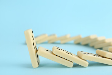 White domino tiles falling on light blue background. Space for text
