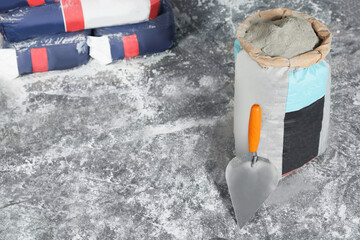Cement powder in bag and trowel on stone floor. Space for text