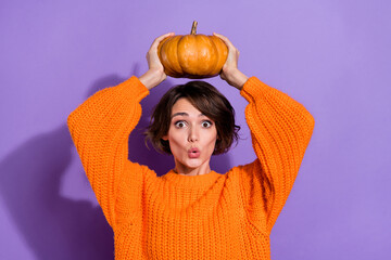 Photo of young pretty girl astonished playful grow big fresh pumpkin isolated over purple color...