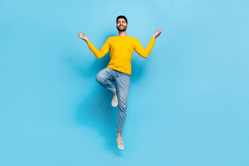 Full body portrait of nice young person jumping hands fingers meditate isolated on blue color...