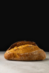 Fresh wheat bun on a light table on a black background