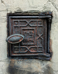 a small rusty metal door in a concrete wall