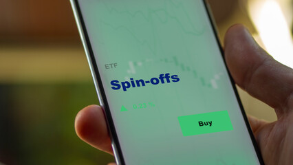 An investor's analyzing the fund etf on screen. A phone shows the ETF's prices spin-offs