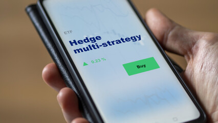 An investor's analyzing the fund etf on screen. A phone shows the ETF's prices hedge multi-strategy