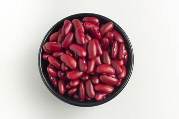 red kidney beans in a bowl on white background, top view, flat lay, top-down, selective focus.
