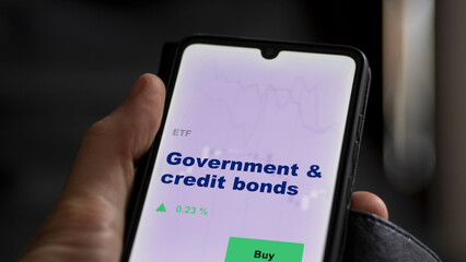 An investor's analyzing the  on screen. A phone shows the ETF's prices government & credit bonds