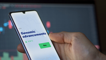 An investor's analyzing the genomic advancements etf fund on screen. A phone shows the ETF's prices genomic advancements to invest