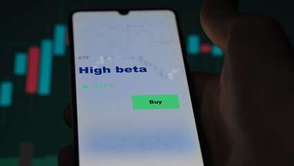 An investor's analyzing the high beta etf fund on screen. A phone shows the ETF's prices stocks to invest