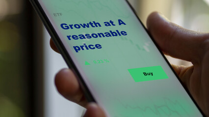 An investor's analyzing the growth at A reasonable price etf fund on screen. A phone shows the ETF's prices stocks to invest