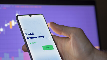 An investor's analyzing the fund ownership etf fund on screen. A phone shows the ETF's prices stocks to invest