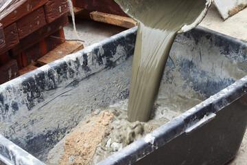 The process of mixing cement at a construction site. Pouring water into a mixture of cement and sand. selective focus