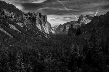 Black and white Yosemite valley with jet exhaust across the sky