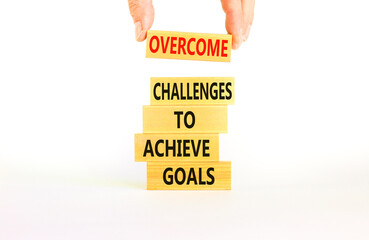 Overcome challenges to achieve goals symbol. Concept words Overcome challenges to achieve goals on wooden blocks on a beautiful white background. Businessman hand. Business goals concept. Copy space.