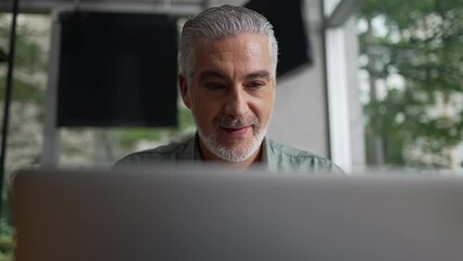 Happy older man using laptop computer at coffee shop. Closeup face of a senior entrepreneur looking at screen working remotely at cafe place - Powered by Adobe