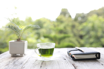 Green tea glass cup and notebook on old wooden table