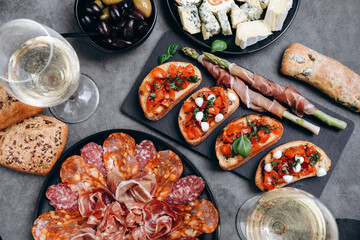 Food antipasto prosciutto ham, salami, olives and grissini bread sticks. cheese on a board...