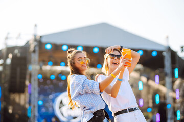 Two young woman  having a great time at a music festival. Happy girlfriends rinking beer and having fun at Beach party. Summer holiday, vacation concept.