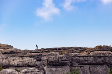 man walking alone in the mountain, panoramic with blue sky and clouds, (El Torcal, Antequera)