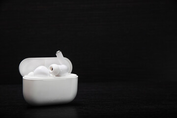 SMALL WHITE WIRELESS HEADPHONES WITH DARK BACKGROUND