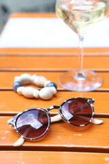 sun glasses lay on white table closeup photo on summer cafe and human hands background