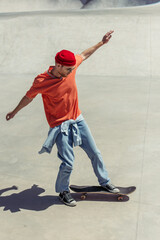 Fototapeta na wymiar full length of stylish man with outstretched hands skateboarding in skate park