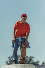 low angle view of man in sunglasses and orange t-shirt holding skateboard outdoors © LIGHTFIELD STUDIOS
