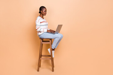 Full side profile photo of boss braids hairdo lady type laptop thumb up wear pullover jeans shoes isolated on beige background