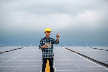 Asian Engineer use tablet working inspection installation solar cell on the roof. Technician maintenance solar cells on roof factory under morning sunlight. Technology solar energy renewable.