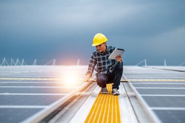 Asian Engineer use tablet working inspection installation solar cell on the roof. Technician maintenance solar cells on roof factory under morning sunlight. Technology solar energy renewable.